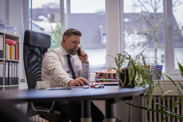 Rechtsanwalt Wolf Heller sitz an seinem Schreibtisch und telefoniert