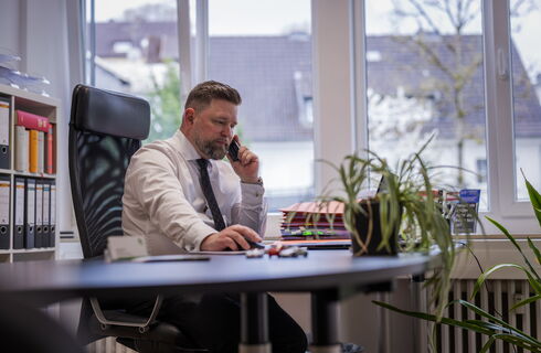 Rechtsanwalt Wolf Heller sitz an seinem Schreibtisch und telefoniert
